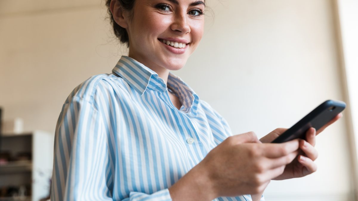 Relaxed West Virginia real estate exam prep student smiling and holding her phone, ready for test day